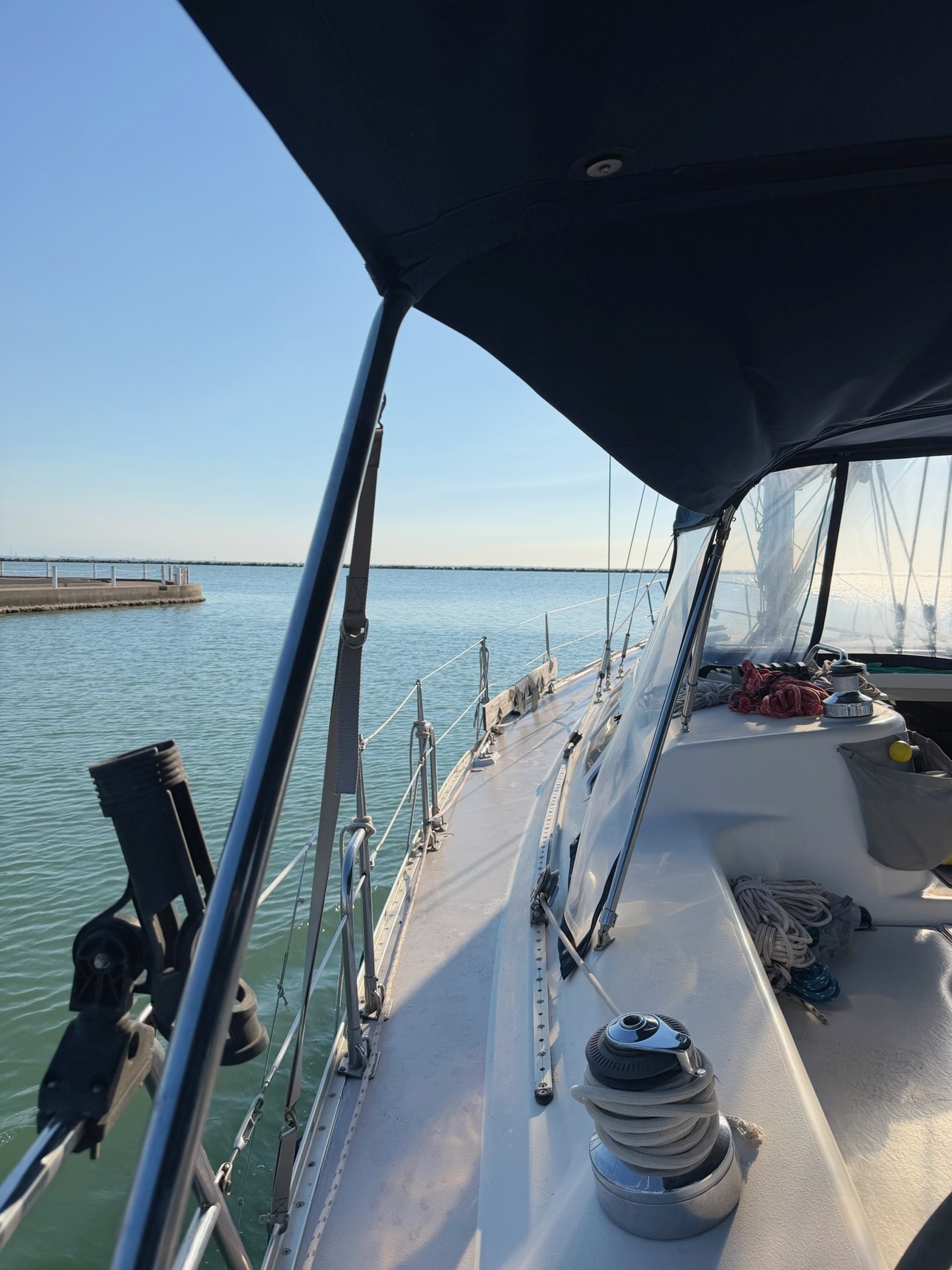 Two people on a small sailboat, relaxed and laughing in morning light